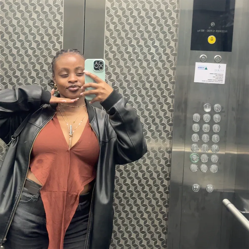 Moreen showing a layered jacket and jewelry in a mirror