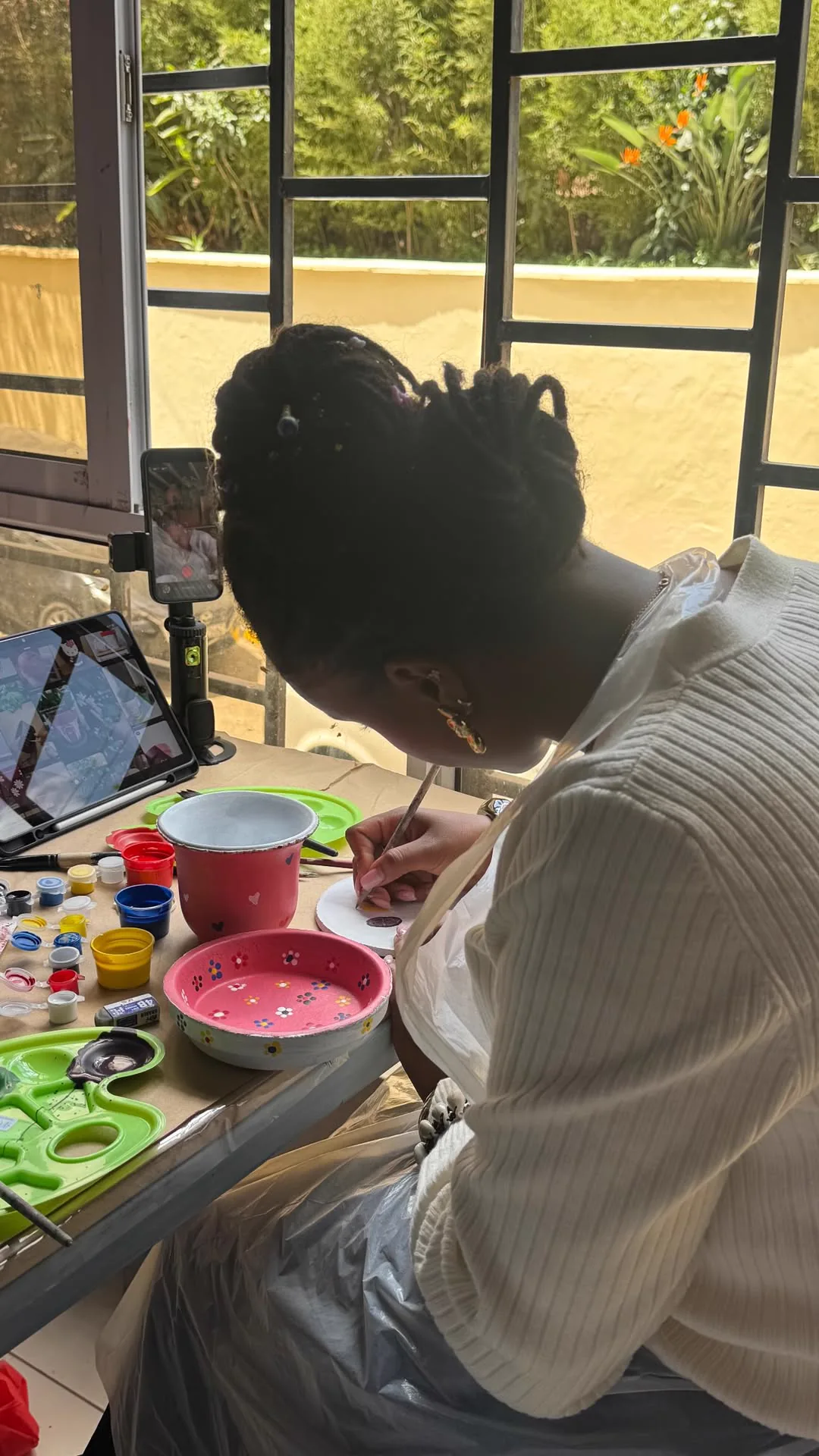 Moreen painting a small ceramic piece at an art table